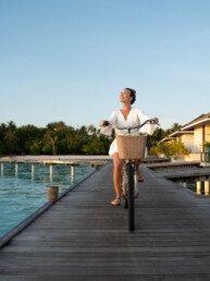 Model riding bike in tropical resort in Maldives
