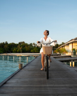 Model riding bike in tropical resort in Maldives