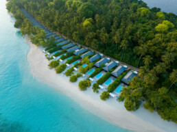Drone view of villas with green and blue scenery in Maldives