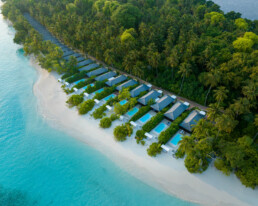Drone view of villas with green and blue scenery in Maldives