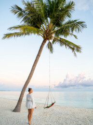 Model standing next to palm tree in Maldives