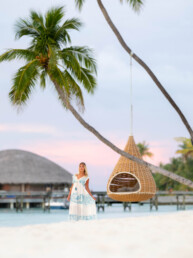 Model beside palm tree and swing in the Maldives