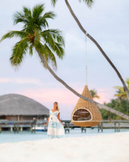 Model beside palm tree and swing in the Maldives